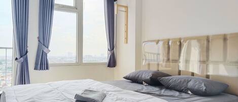 Una habitación de hotel con cama, ventana con cortinas y vista a la ciudad.