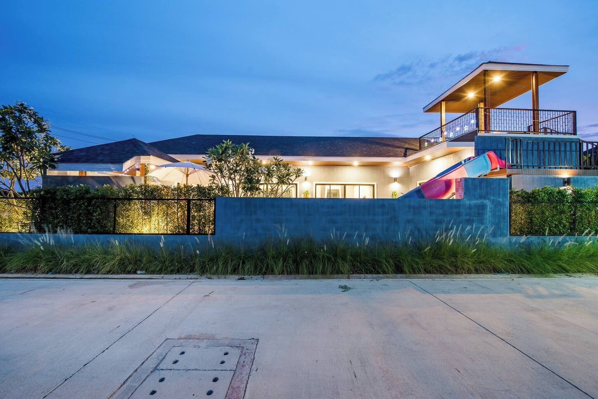 A modern building with a large slide, a covered outdoor area, and a view of the surrounding landscape.