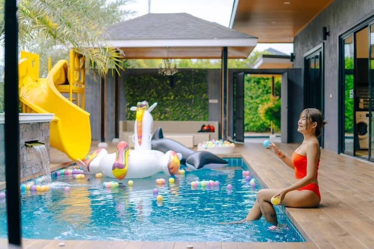 Une piscine avec des jouets gonflables et une personne vêtue d’un maillot de bain rouge, assise au bord de la piscine.