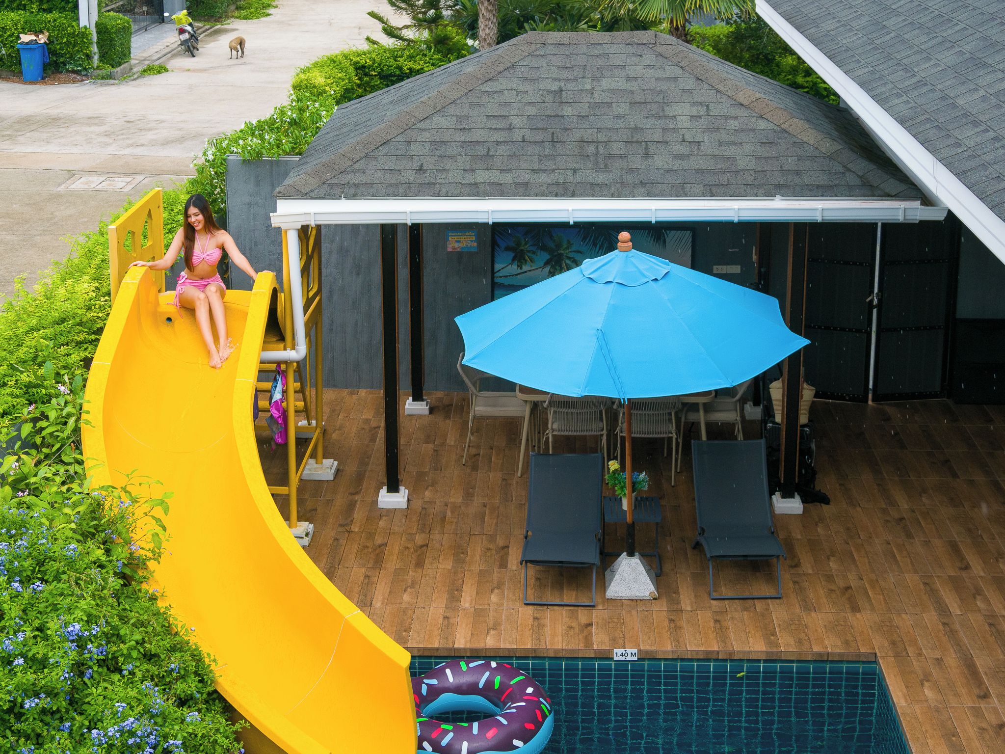 Uma área de piscina com escorregador, espreguiçadeiras e guarda-sol.