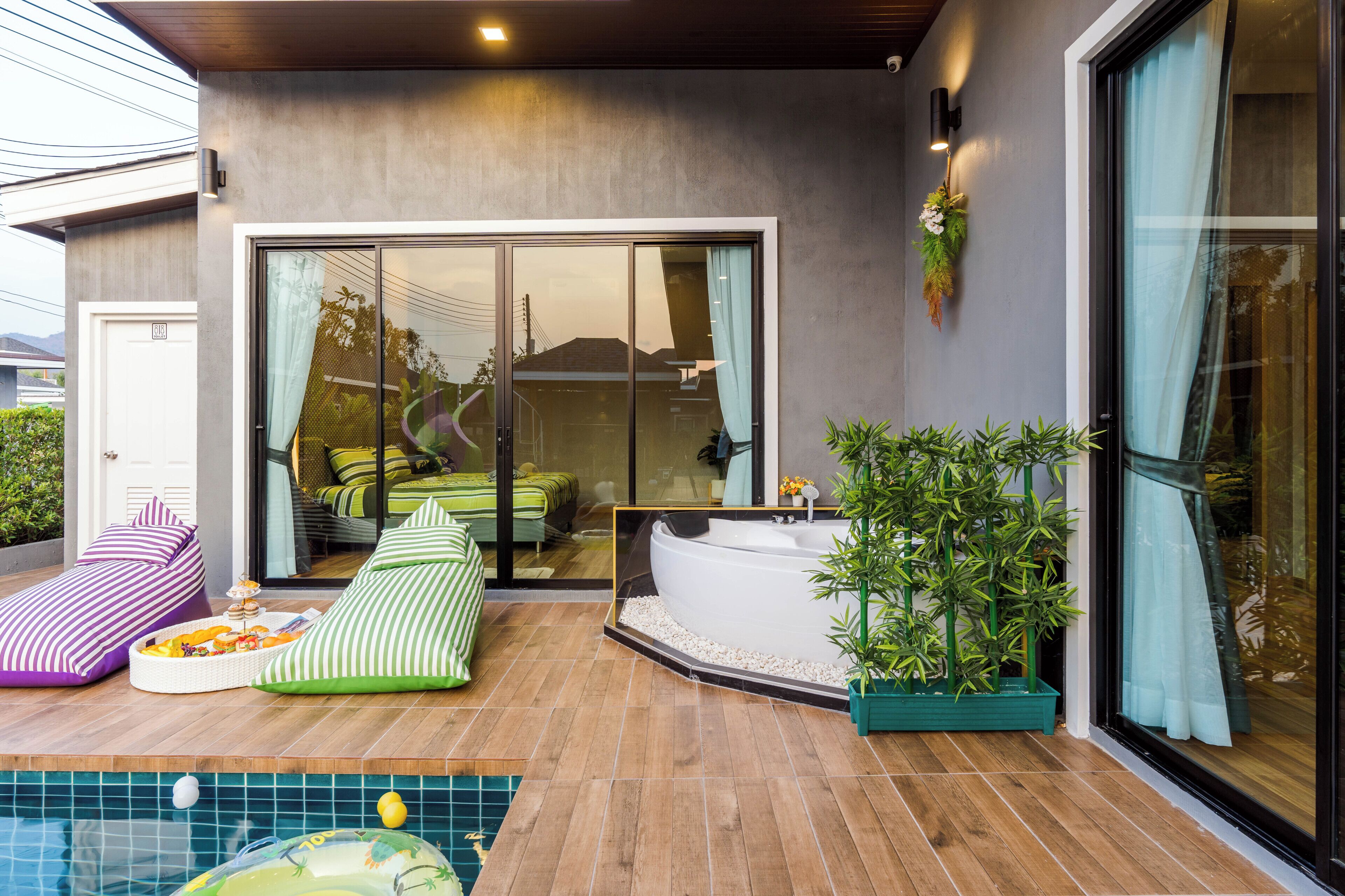 A modern outdoor living area with a pool, lounge chairs, and a hot tub.