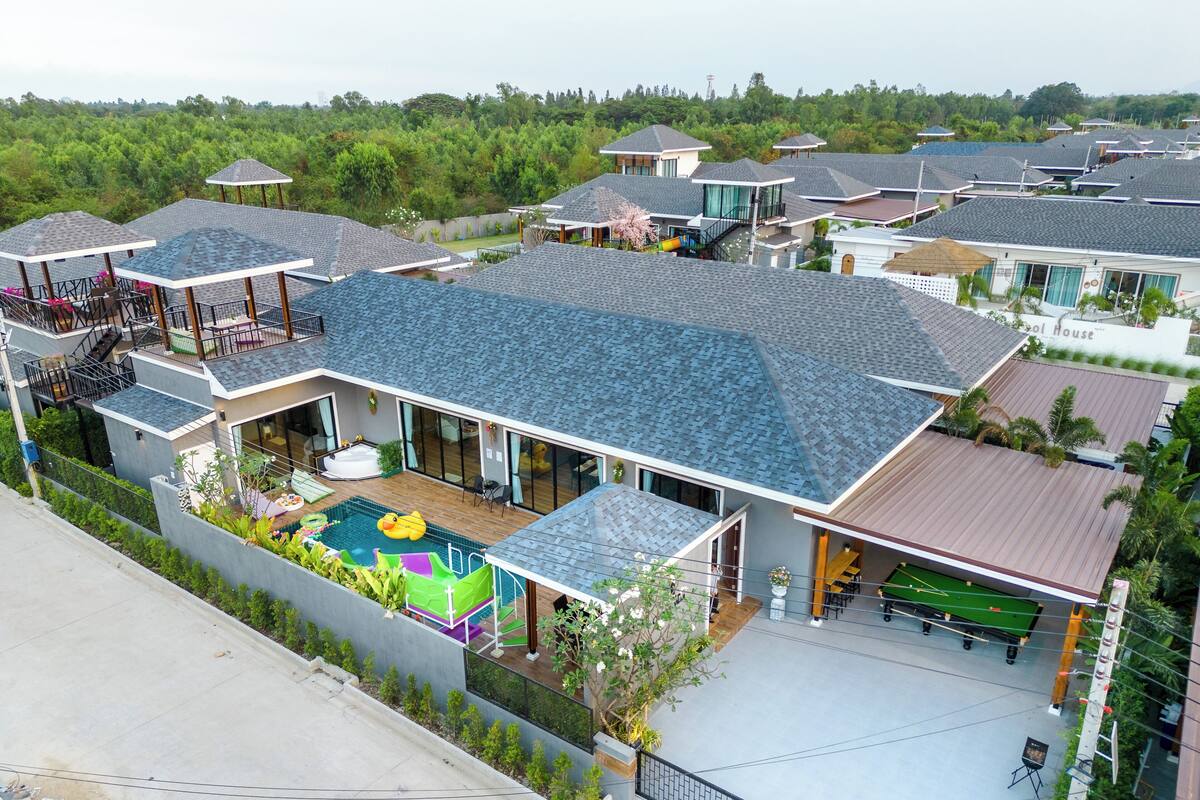 Un complexe résidentiel moderne comprenant plusieurs maisons, une piscine à usage collectif et un court de tennis.