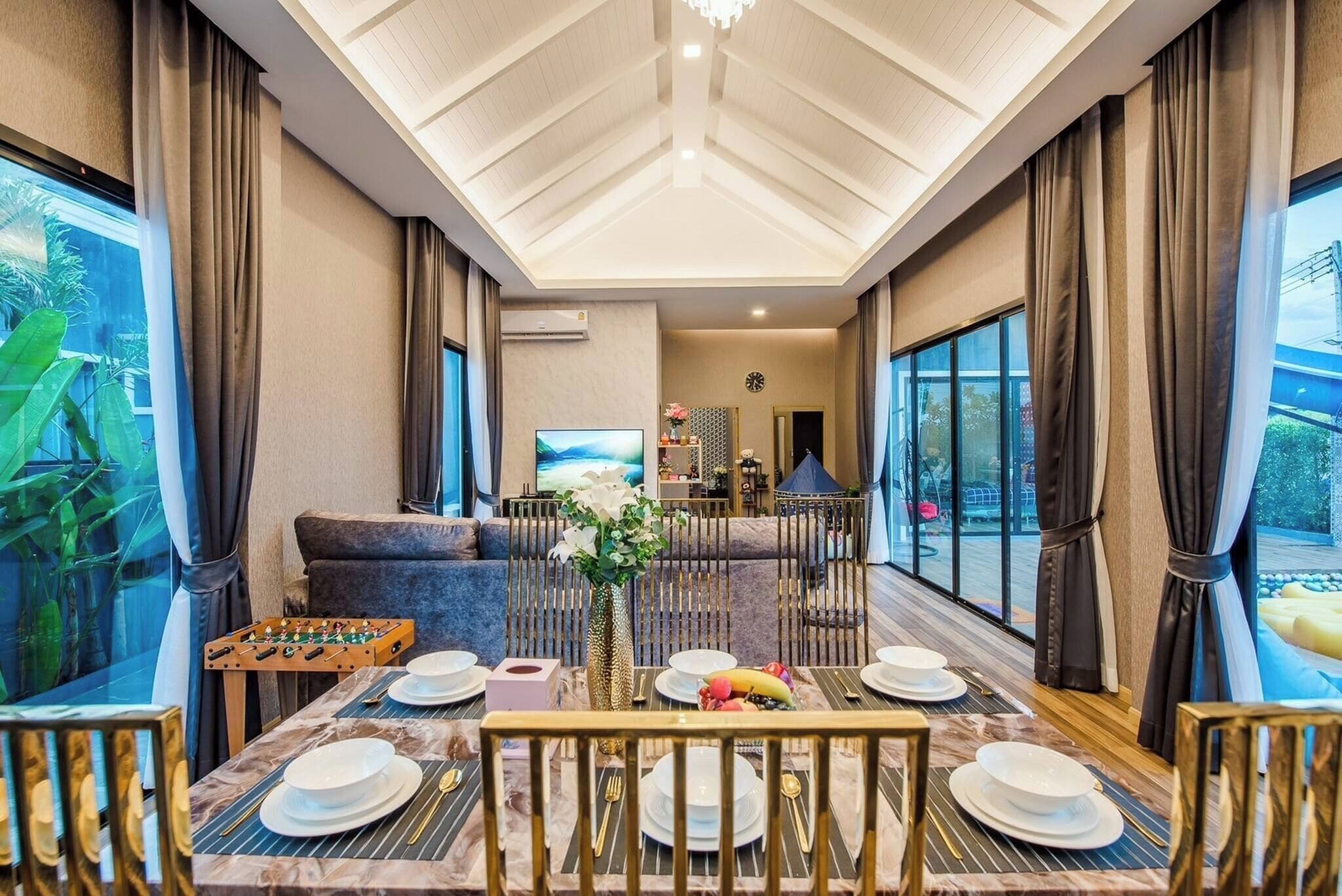 A dining area with a table set for four, a sofa, and a TV in the background.