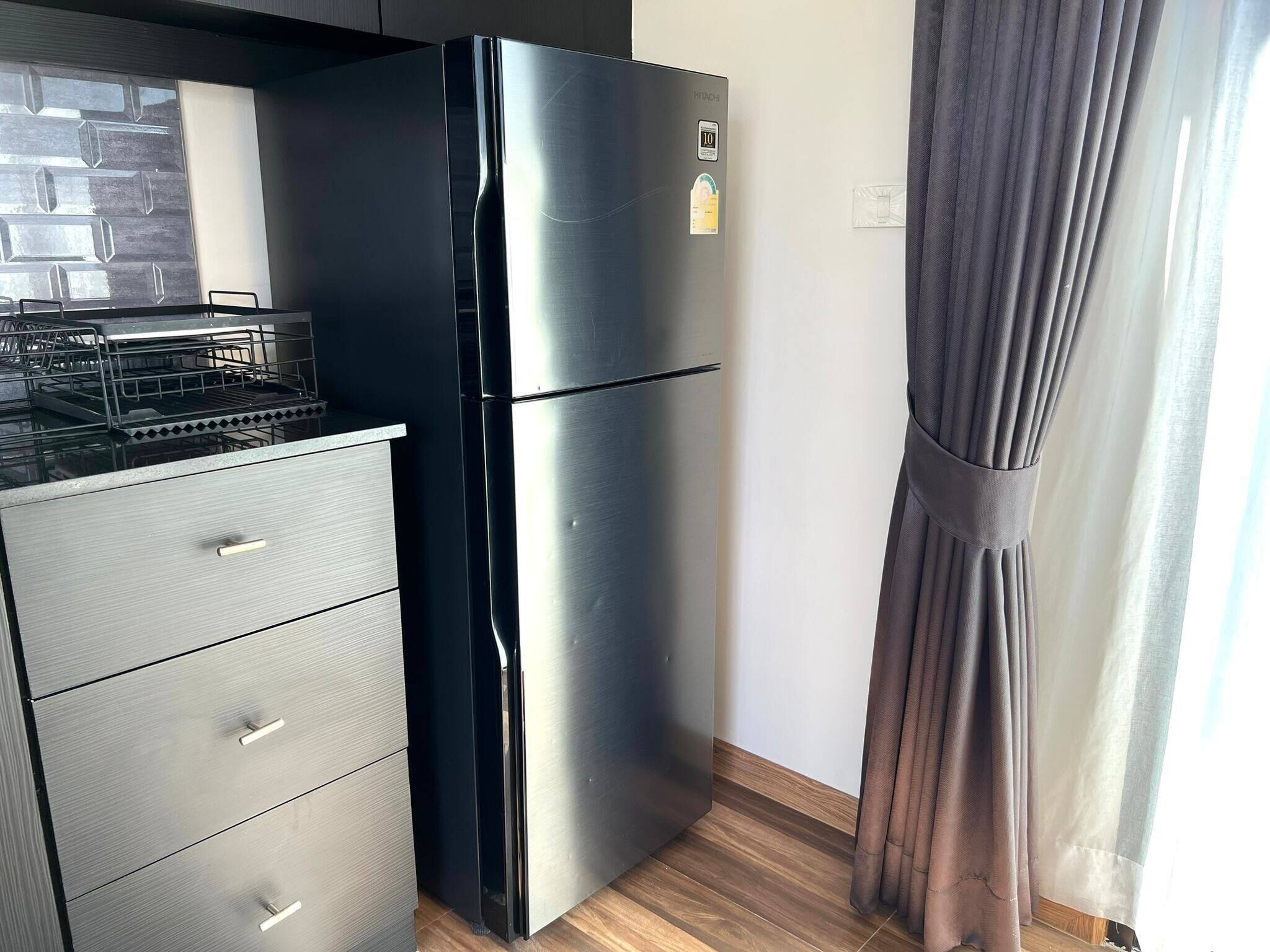 Une cuisine de taille réduite avec un réfrigérateur noir, un four encastré et un plan de travail en bois.