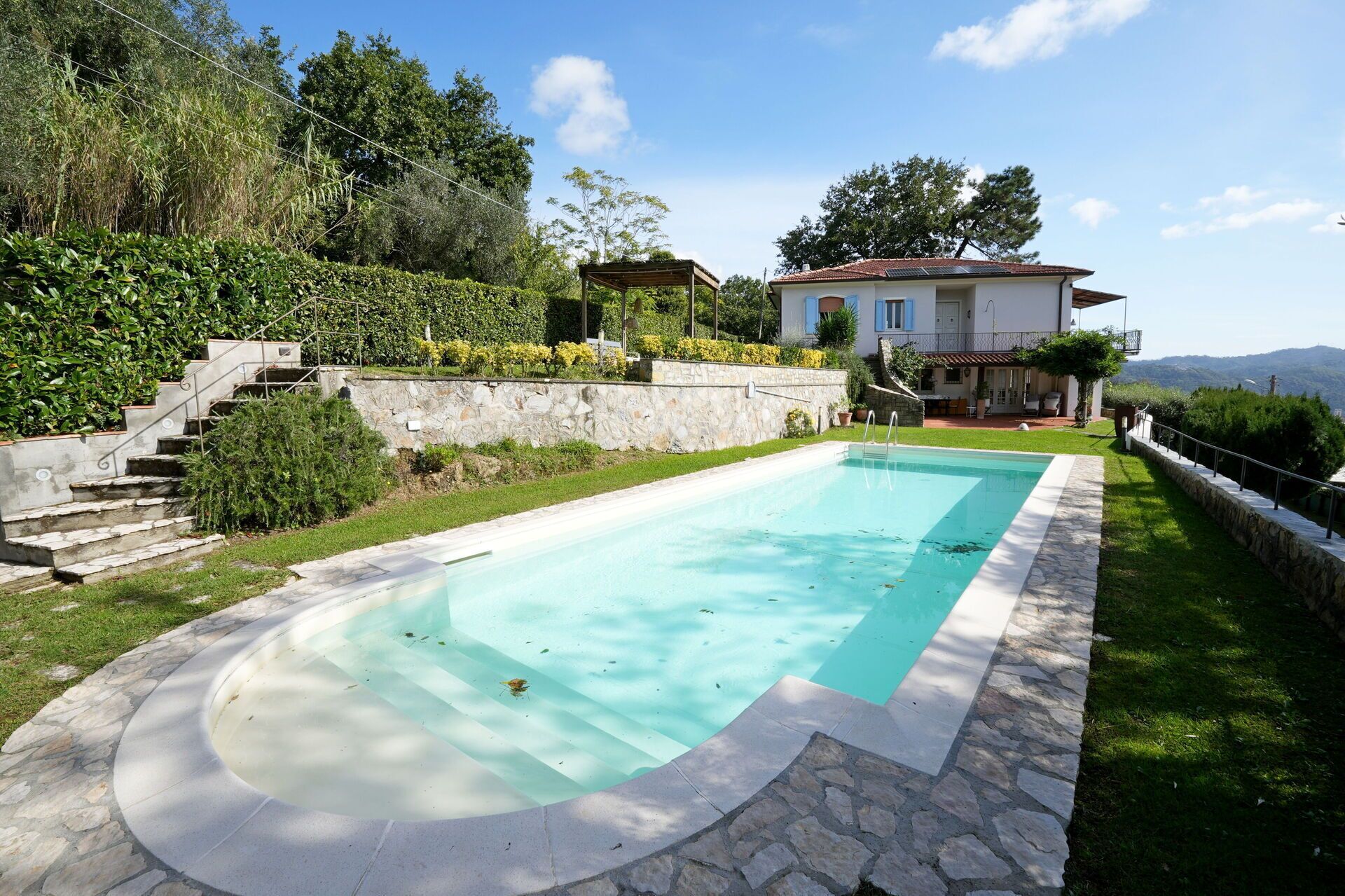 Une piscine rectangulaire bordée de pierres, entourée d’un escalier en pierre et d’un mur en pierre.