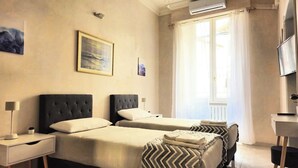 A hotel room with two beds, a desk, a chair, and a TV. - Rome Boulevard Suite - In the heart of Rome, just minutes from St. Peter's Square, (Roma)