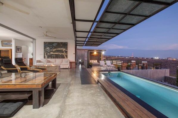 Un área de piscina interior moderna con vistas al horizonte de la ciudad al anochecer.