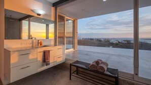 A modern bathroom with a large mirror, a sink, and a bench with towels. - Villa Wellmina - Stunning Sunsets & Relaxing Poolside Vibes! (La Paz)