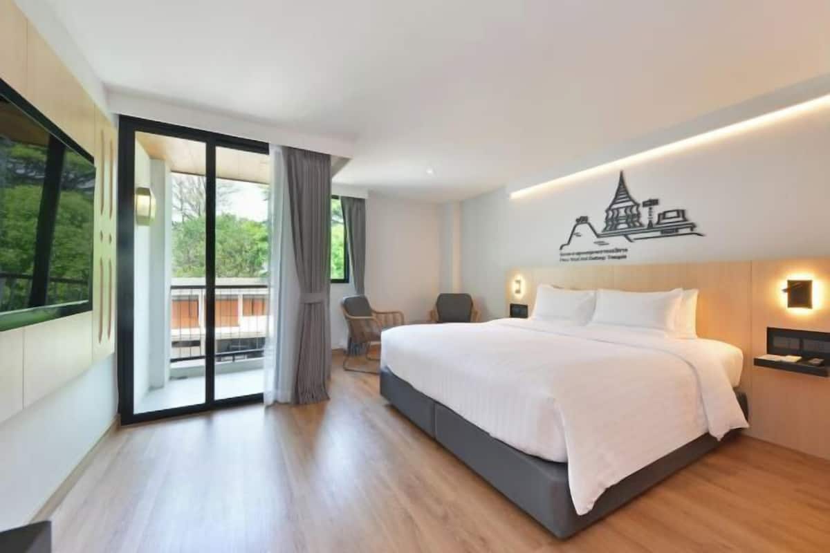 Una habitación de hotel moderna con una cama grande, una silla, un escritorio y vistas a través de una puerta corredera.