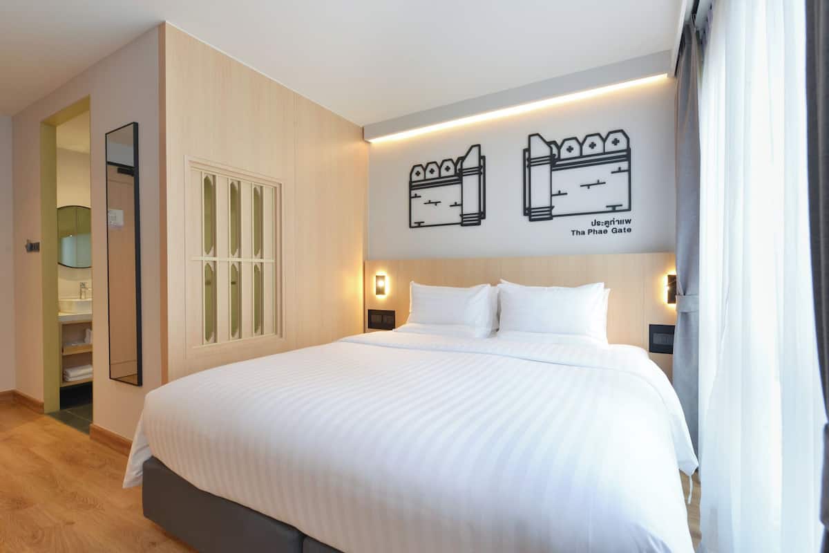 Una habitación de hotel con una cama grande, un armario, un espejo y un mapa mural.