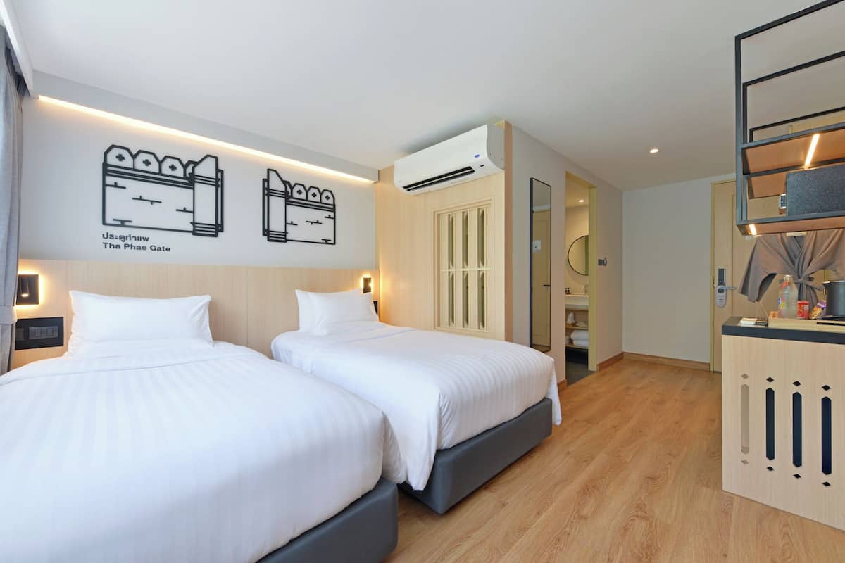 Habitación de hotel con dos camas, un armario, un equipo de aire acondicionado y una pared con un mapa.