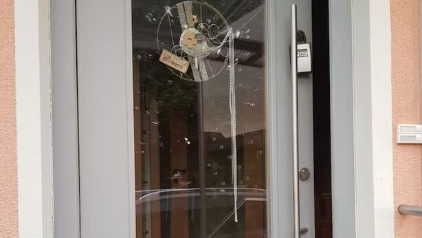 A modern door with a glass panel, a metal handle, and a small sign above the door. - Modern 2-room attic apartment in the heart of the Rhön (Ostheim vor der Rhön)