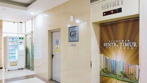 A hotel lobby with a vending machine, a service desk, and a poster advertising Sentra Timur Residence. - The Royale Sentra Tower Kuning (Jakarta)