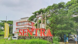 A building with a large red sign reading "SENTRA". - The Royale Sentra Tower Kuning (Jakarta)