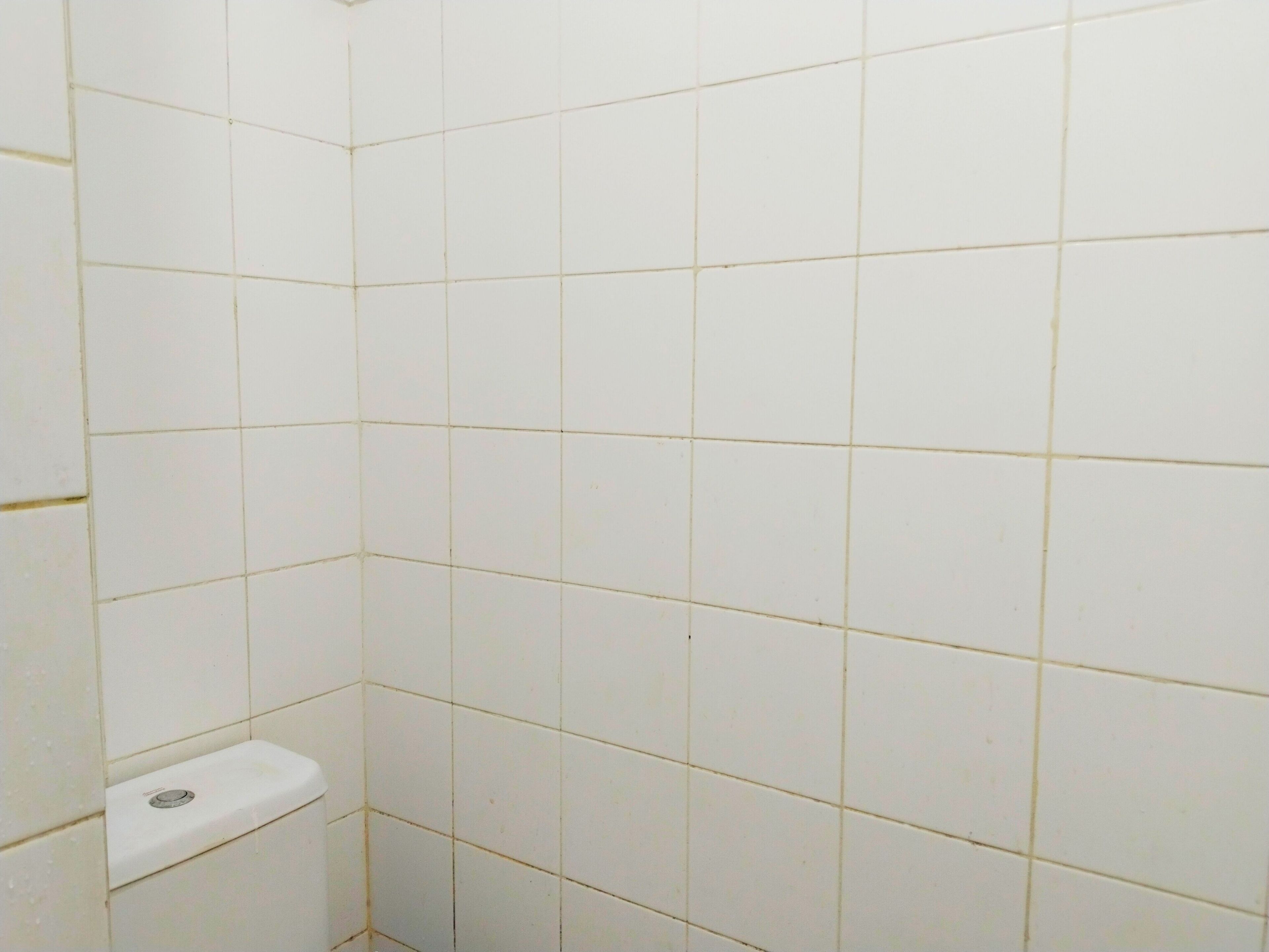 Un baño con azulejos blancos, un lavamanos blanco y desagüe visible.