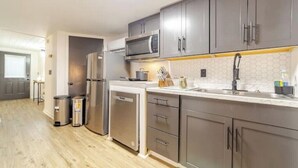 A modern kitchen with grey cabinets, stainless steel appliances, and a white countertop.