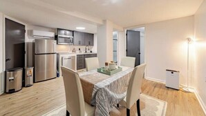 A modern kitchen with stainless steel appliances, a dining area with a table and chairs, and a compact refrigerator.