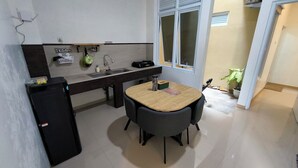 Eine kompakte Küche mit Spüle, einem kleinen Kühlschrank und einem Esstisch mit zwei Stühlen.