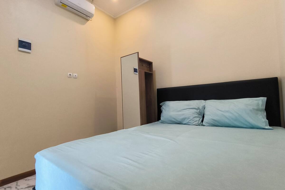 A hotel room with a bed, a wardrobe, and an air conditioning unit.