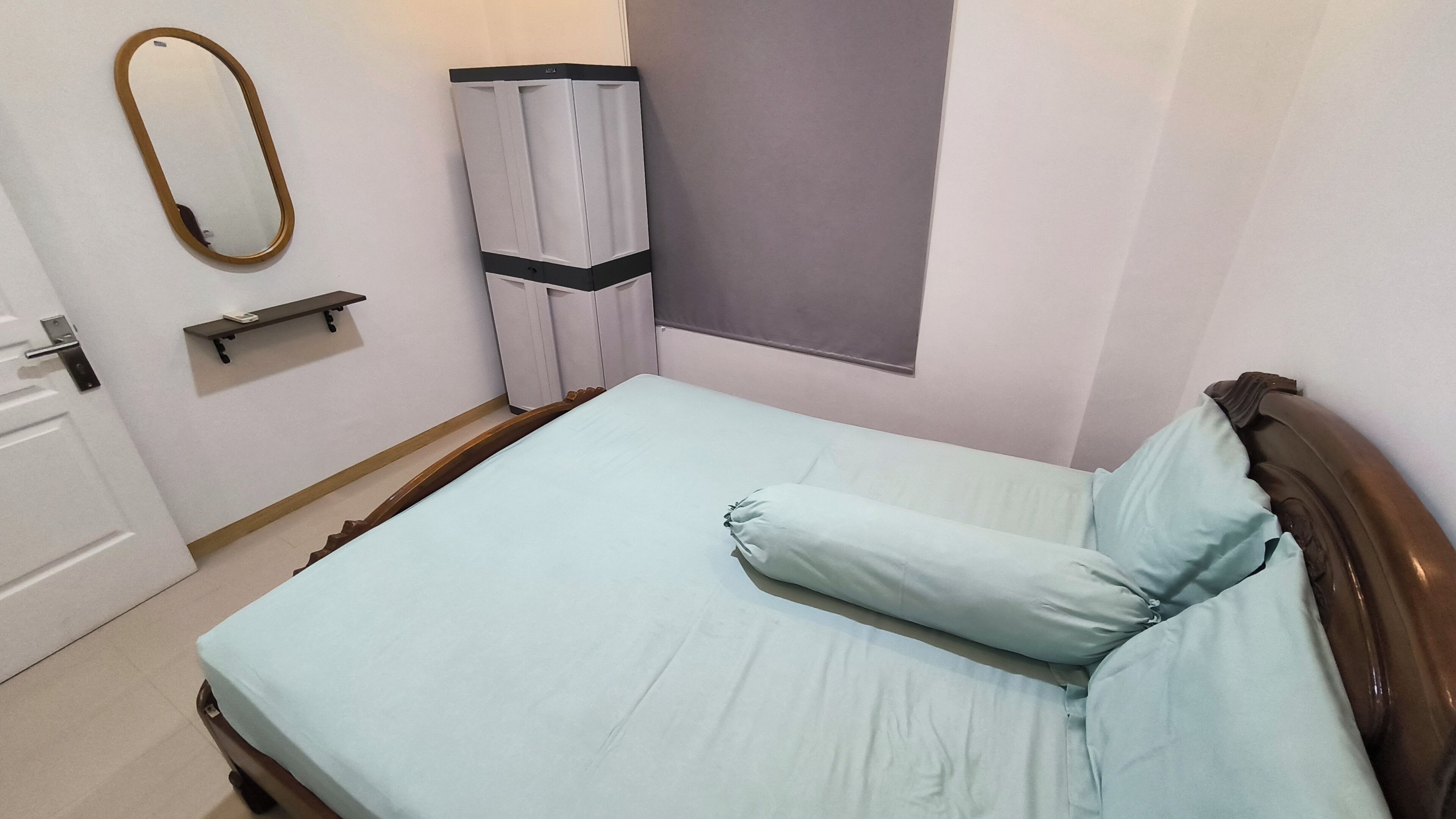 Un dormitorio con cama, espejo, armario y ventana.