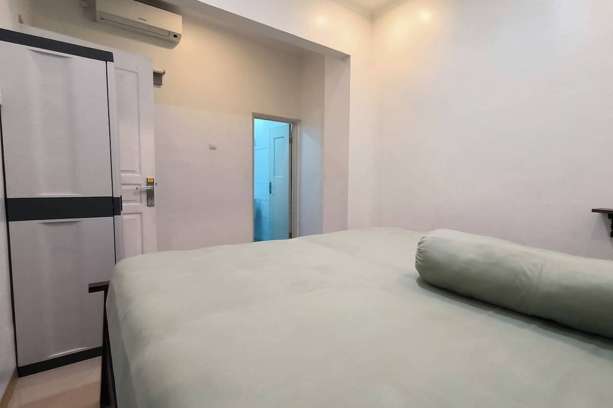 A bedroom with a bed, a wardrobe, and a door leading to another room.