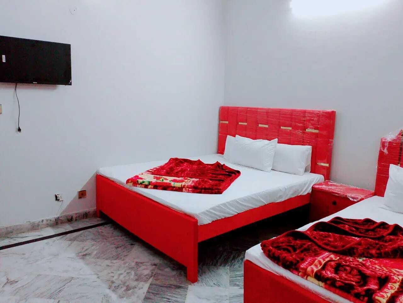 Ein Zimmer mit zwei Betten, jeweils mit rotem Kopfteil und weißer Bettwäsche.