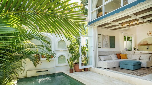A poolside area with a pool, potted plants, and a seating area with a sofa and ottoman. - Tropical 1BR Private Pool Villa, 8 mins to beach In Uluwatu (Pecatu)