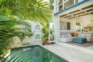 A poolside area with a pool, potted plants, and a seating area with a sofa and ottoman. - Tropical 1BR Private Pool Villa, 8 mins to beach In Uluwatu (Pecatu)