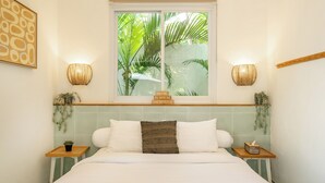 A bedroom with a bed, two bedside tables, a window with a view of greenery, and wall-mounted sconces. - Tropical 1BR Private Pool Villa, 8 mins to beach In Uluwatu (Pecatu)