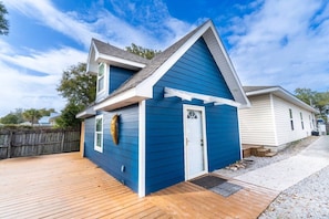 A two-story house with a blue exterior, a front porch, and a wooden deck.