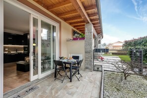 An outdoor patio with a table and chairs, a stone pillar, and a view of the backyard. - Residence Due Laghi (Ispra)