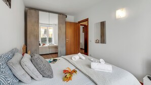 A modern hotel room with a bed, pillows, a bedside table, a nightstand, a mirror, and a wardrobe. - Residence Due Laghi (Ispra)