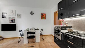 A modern kitchen with black cabinets, a white countertop, and a dining area with chairs. - Residence Due Laghi (Ispra)