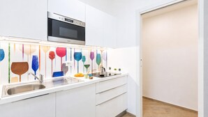 Una cocina moderna con armarios blancos, un lavamanos de acero inoxidable y un horno empotrado.