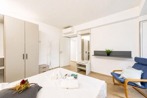 A modern hotel room with a bed, a blue chair, a wardrobe, and a small plant on a shelf. - Central Flat With Private Parking in Genova (Genoa)