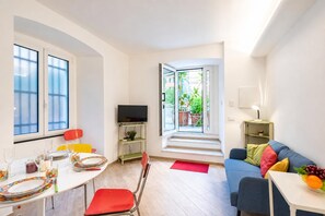 Un salon moderne comprenant un coin repas, un téléviseur et un canapé avec des coussins.