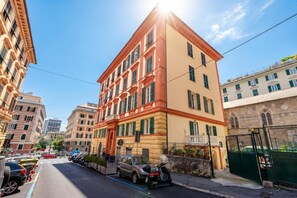 A multi-story building with a classic architectural style, featuring a prominent entrance with a red door and a balcony. - Central Flat In Genova (Genoa)