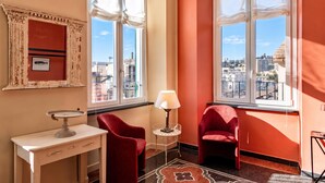A room with a city view, a red chair, a white table, and a lamp. - Precious House Genova Porto Antico (Genoa)