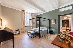Una camera da letto con un letto a baldacchino, un pianoforte, un tavolino in legno e un bouquet di fiori.