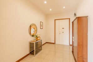 A hallway with a wooden cabinet, a glass display cabinet, a framed picture, and a door. - Bright Apartment Private Parking Naples (Naples)