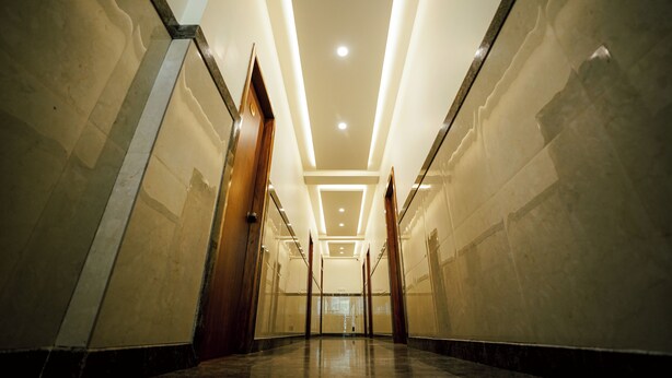 A hallway with a polished floor, recessed lighting, and mirrored walls. - The Ekah Comforts  (Bengaluru)