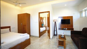 A hotel room with a bed, wardrobe, desk, TV, and a sofa. - The Ekah Comforts  (Bengaluru)