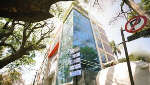 A modern building with a glass facade, a no parking sign, and a covered vehicle nearby. - The Ekah Comforts  (Bengaluru)
