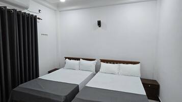 A hotel room with two beds, a ceiling fan, an air conditioning unit, a small bedside table, and a nightstand.