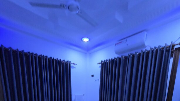 A bedroom with a bed, curtains, a ceiling fan, and an air conditioning unit. - Munril Guest (Jaffna)