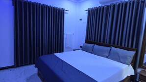 A bedroom with a bed, curtains, and an air conditioning unit. - Munril Guest (Jaffna)