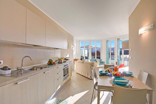 A modern kitchen with a dining area, large windows, and a view of the outdoors.