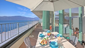 A balcony with a table set for dining, overlooking a body of water and mountains. - Sogno Sul Lago, Lakefront Balcony (Laveno Mombello)