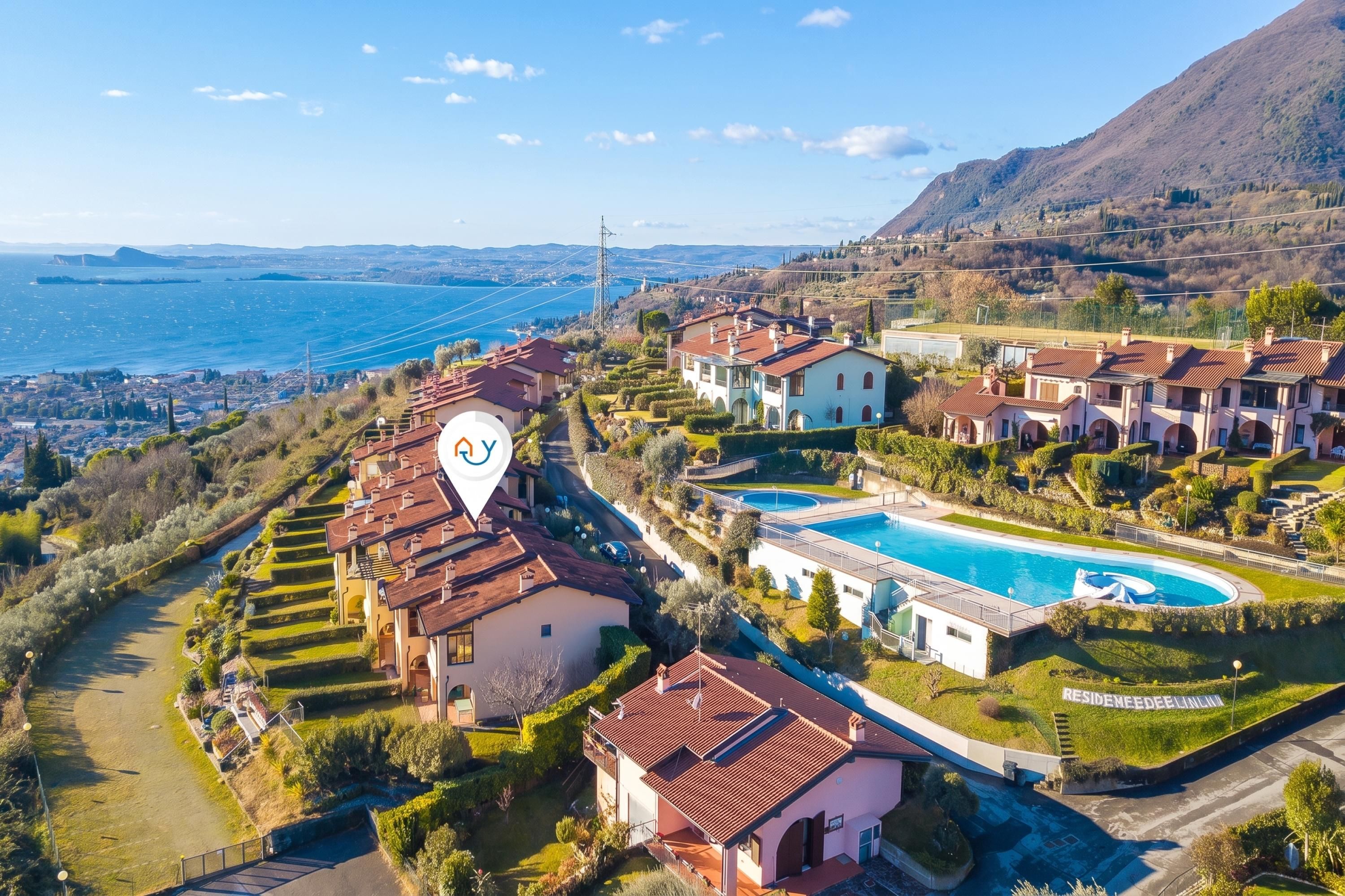 A residential area with houses, a swimming pool, and a view of the sea.