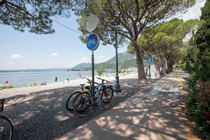 A paved pathway with bicycles parked, a beach in the background, and a clear sky. - Julia's House With Lakeview and shared pool (Toscolano Maderno)